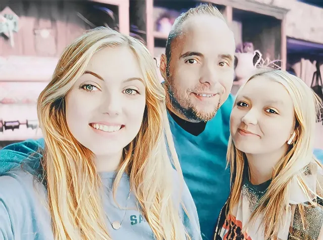 A man and two women posing for the camera.